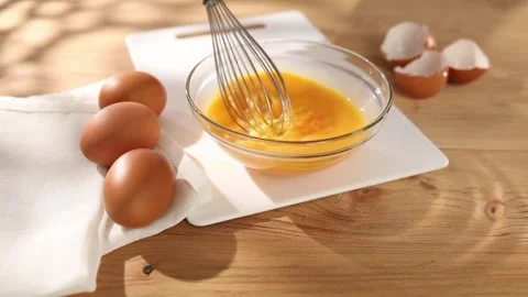 Whisking eggs. Man whisking raw eggs in a bowl. Close -up. 4k footage. Stock Footage 242992060