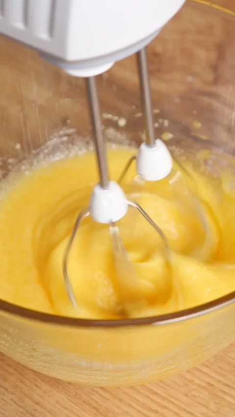 Whisking fresh egg yolks with an electric mixer in a glass bowl for cooking 库存影片 342906816