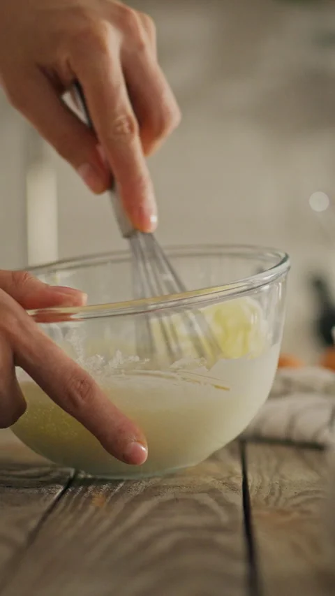 Whisking ingredients in a clear bowl on a rustic wooden countertop during da Stock Footage 331738783