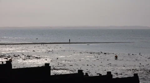 Whistable Beach U.K, View of lone person walking a narrow peninsula into the sea Stock Footage 63919161