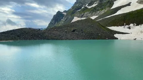 White Abudelauri Lake rippling below lingering snowfields Stock Footage 340387621