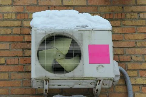 White air conditioning part of a split system hanging on a brick wall of a bu Stock Photos