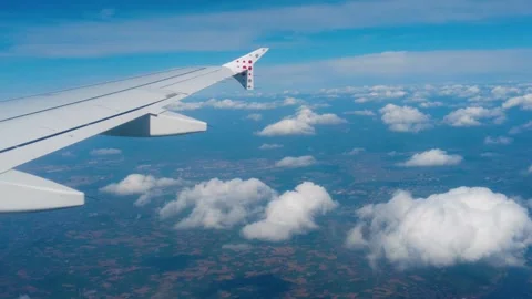 White airplane wing dotted wingtip stretches above scattered fluffy clouds Stock Footage 326359599