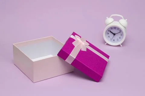 White alarm clock on the background of an open gift box for the holiday. time Stock Photos