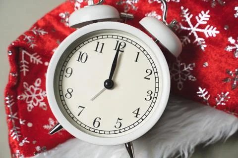 White alarm clock lying on the background of a new year red cap, new year Stock-Fotos