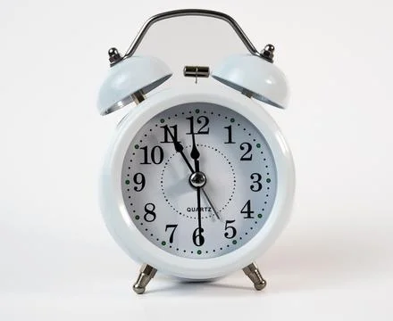 White alarm clock showing almost midnight isolated on white background Stock Photos