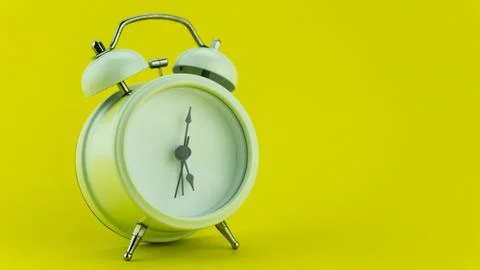 White alarm clock on yellow table background. Stock Photos