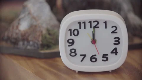White Analog Alarm Clock On Brown Table Stock Footage 260292575