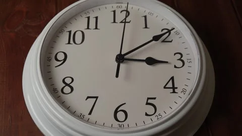 White analog wall clock on dark wooden background close up Stock Footage 345432748