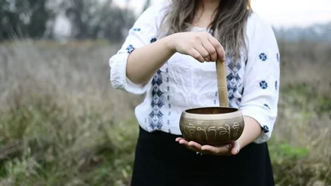 White and black dressed buddhist woman playing a tibetan bowl with wooden stick Stock Footage 194749683