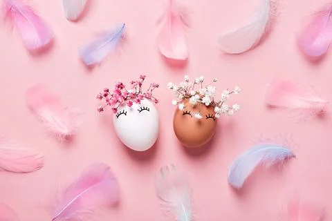 White and black Easter eggs with natural flowers wreath on soft pink feathers Stock Photos