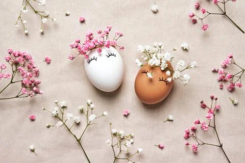 White and black Easter eggs with natural flowers wreath on linen background Stock Photos