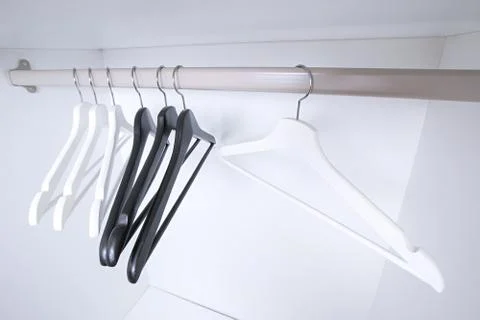 White and black empty clothes hangers, in the wardrobe Foto stock