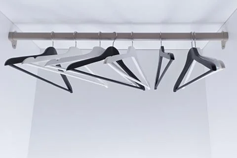 White and black empty clothes hangers, in the wardrobe Stock Photos
