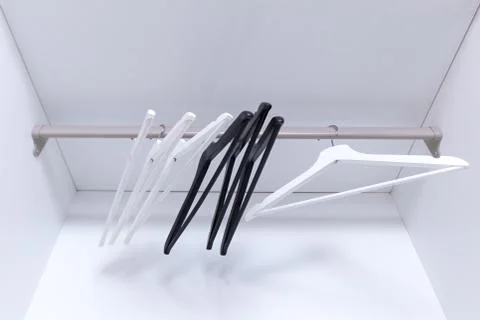 White and black empty clothes hangers, in the wardrobe Stock Photos