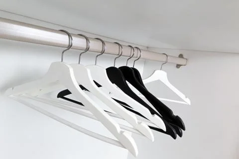 White and black empty clothes hangers, in the wardrobe Stock Photos