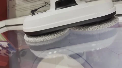 A white and black robot is cleaning a white plate Stock Footage 282760445