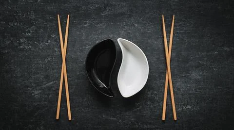 White and black yin yan bowls and chopsticks on grunge background with copy s Stock Photos