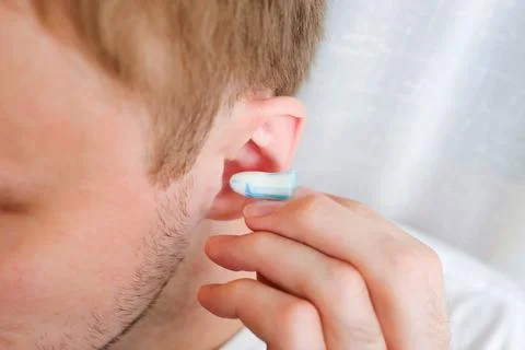 White and blue ear plug puts in the ear Foto stock