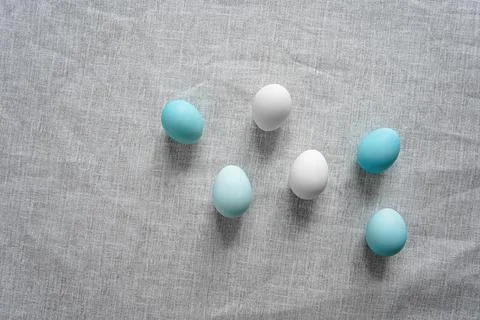 White and blue Easter eggs on grey linen cloth Stock Photos
