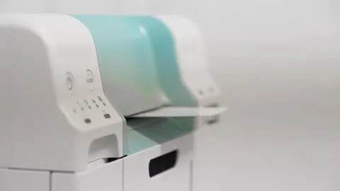 A white and blue printer with a green handle. The buttons on the printer are  Stock Footage 344908772