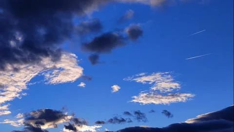White and dark clouds time lapse on blue sky, and 2 aiplane contrails 動画素材 292153036