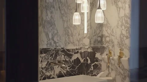 White and dark marble bathroom with hanging warm pendant lights above modern Stock Footage 328482696