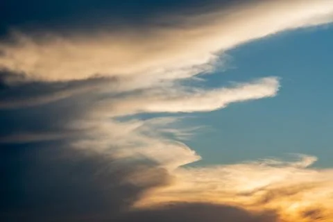 White and gray clouds are illuminated by the bright light of the setting sun. Stock-Fotos