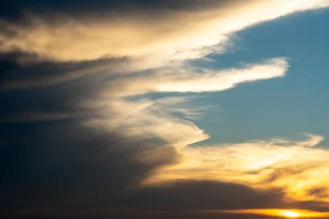 White and gray clouds are illuminated by the bright light of the setting sun. Stock-Fotos