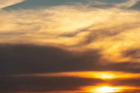 White and gray clouds are illuminated by the bright light of the setting sun. Stock-Fotos