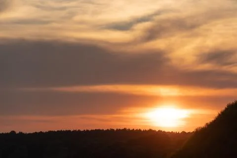 White and gray clouds are illuminated by the bright light of the setting sun. Stock-Fotos