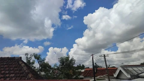 White and gray clouds with blue sky above the roofs of the village houses. Stock Footage 274153314
