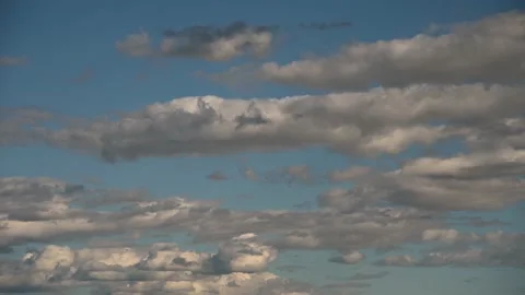White and gray clouds moving slowly through a crisp light blue sky. Stock Footage 142888300