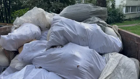 White and gray plastic bags with construction debris in metal dumpster Vídeos de archivo 344041447