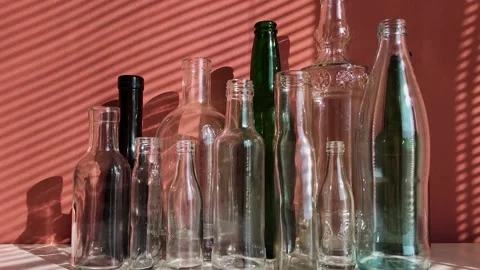 White and green glass empty bottles are on a table, illuminated by the sun Stock Footage 303929299