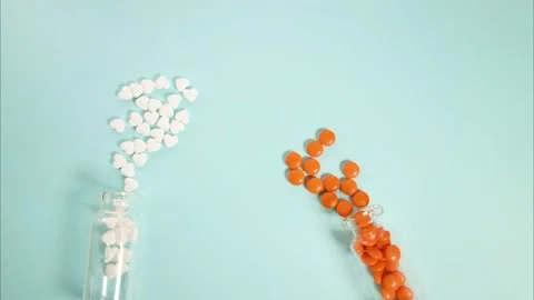 White and orange tablets are poured from one jar to another. The tablets are Stock Footage 143617683