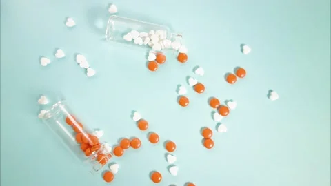 White and orange tablets are collected in glass jars. Stop motion video. Video stock 144100584