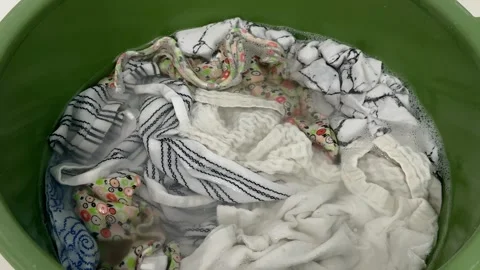 White and patterned clothes soaking in soapy water  Video stock 342438102