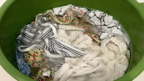 White and patterned laundry soaks in soapy water  Stock Footage 341950303