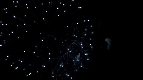 White and pink fireworks explode in dark night sky Stock Footage 329676141