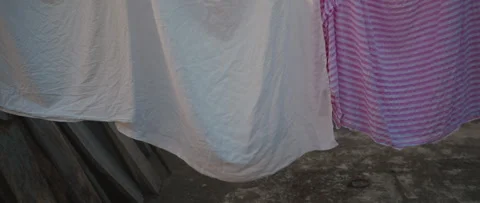 White and pink striped sheets hung on a clothesline outdoors, gently billow.. Stock Footage 337022074