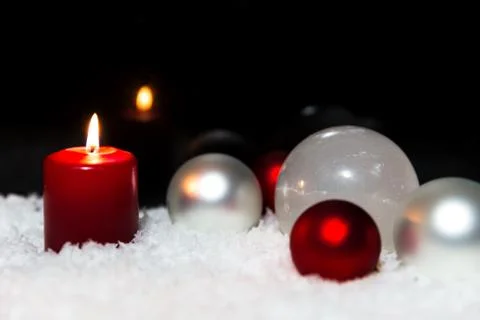 White and red baubles, candle in the snow, black background Fotos Stock