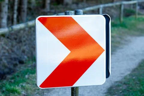 White and red directional chevron warning sign on trail Stock Photos