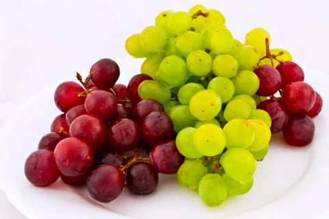 White and red grapes on a white plate Stock Photos