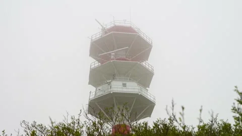 White and red lighthouse tower rising above green shrubbery under overcast .. Stock Footage 335288529