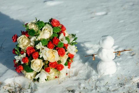 White and red rose wedding bouquet in in the snow and wedding rings on a snowman Foto stock