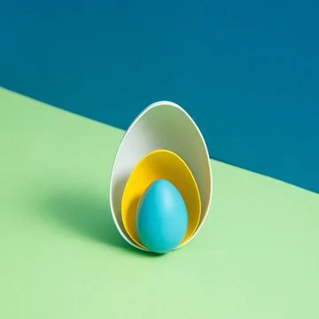 White and yellow eggshells and the whole blue Easter egg on blue and green ba Stock Photos
