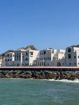 White Arabic style seafront palace in Muscat, Oman with mountains and blue sky Stock Photos