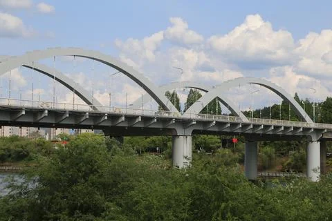 White arched bridge with repeating spans against blue sky and large cumulus.. Stock Photos