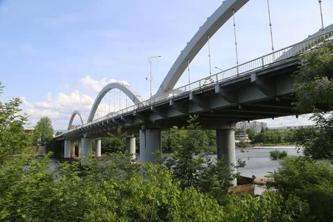White arched bridge seen from below with green foliage and river water beneat Stock Photos